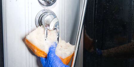 Cleaning of shower steam cabins from calcium deposits. Cleaning in the bathroom. hand in gloves with...