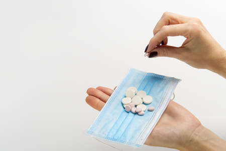 concept covid vaccine pills. COVID-19. Medical mask on a hand with white background. Medicine pills...
