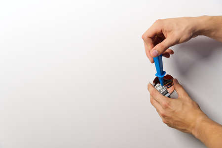 electrician installing light switch on painted wall with screwdriver. Man installing light switch...