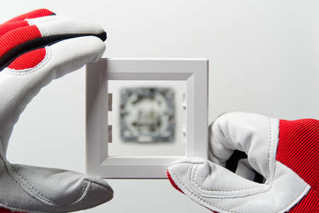 Man installing light switch after home renovation. Electrician installing light switch on painted wall with screwdriver.の写真素材