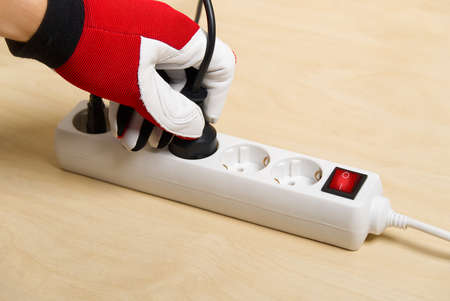 Mans hand plugging extension cord. Closeup of an electrician plugging extension cords into each other.の写真素材