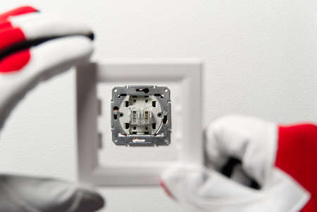 Man installing light switch after home renovation. Electrician installing light switch on painted...