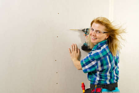 blonde woman with screwdriver tool in hands working at home improvement. handywomen conceptの写真素材