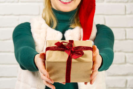 Female hands holding a small gift box wrapped in packing paper. To give and receive gifts from loved...