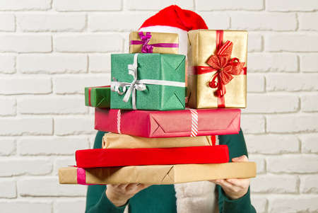 unrecognizable woman holding many christmas gifts. woman holding a lot of boxes with giftsの写真素材