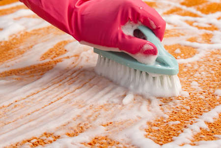 Woman Hand Cleaning Stain On Carpet With hard brush. Orange carpet cleaning. carpet cleaning service conceptの写真素材