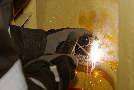 Professional welder welding with electric old metal pipes for heating. Old heating system renovation...