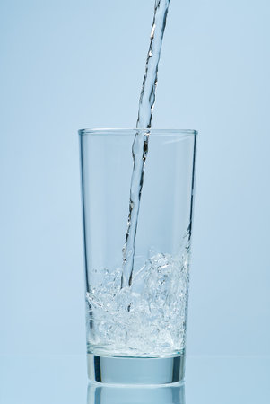 Pouring water. Pouring fresh clean drinking water to glass.の写真素材