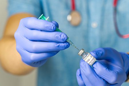 doctor dials the vaccine into a syringe. a nurse with a vaccine and a syringe in her handsの写真素材