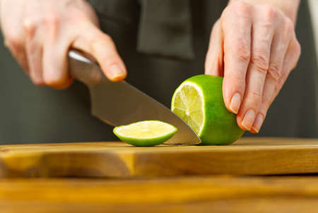Woman cutting lime in kitchen, lemon water, Refreshing Water with lime and lemon, healthy eating conceptの写真素材