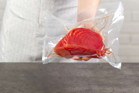 seller at a fish market holding a bluefin tuna steak packed in a vacuum bagの写真素材
