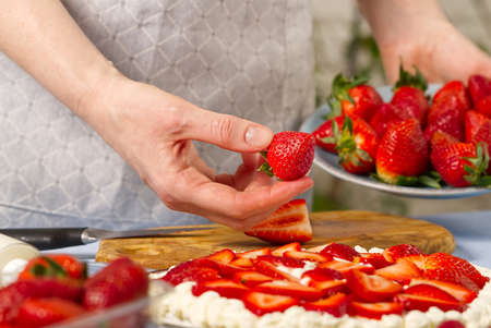 chef decorating delicious dessert with fresh strawberry, strawberry cake.の写真素材