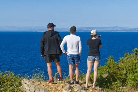 friends looking on a cliff above the sea, hikers looking at view and enjoying enjoy climbing to the top. Active lifestyle.の写真素材