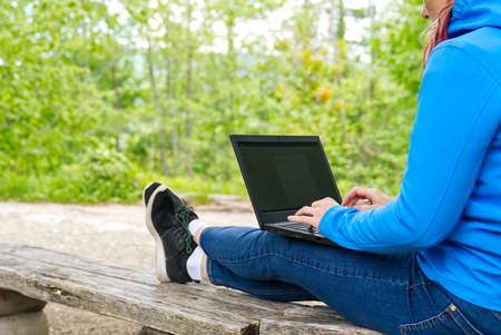 Work from anywhere. Remote freelancer work in nature. Young woman, female freelancer working with laptop with Beautiful view of forest and lake. freelancer paradise, freedom of teleworking. distance work. freelance job at publick parkの写真素材