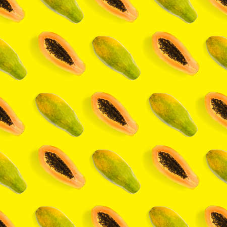 Fresh ripe papaya seamless pattern on yellow background. Tropical abstract background. Top view. Creative design, minimal flat lay concept. Trend tropical fruit food background patternの写真素材