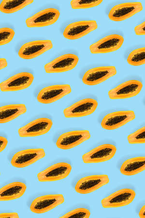 Fresh ripe papaya background on blue backdrop. Modern tropical abstract background. Top view. Creative design, minimal flat lay concept. Trend tropical fruit food background - not seamless patternの写真素材