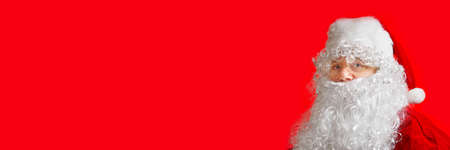 portrait of a man dressed as santa claus on a red background. copy space, banner .