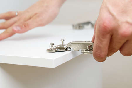 the carpenter screws the hinge on the furniture door. DIY Furniture assembly service concept