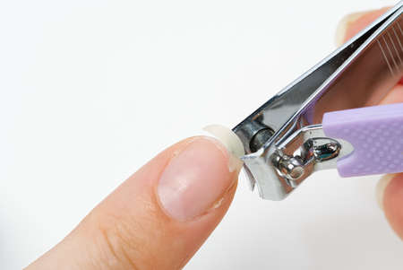 Home nail care. A girl cuts a fragile broken nail on her hand. Brittle fingernail concept.の写真素材