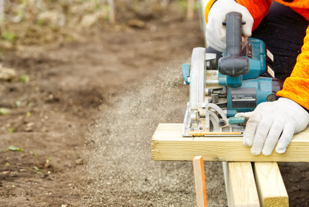 hand circular saw, carpenter sawing wood boards with a hand-held circular saw in the streetの写真素材