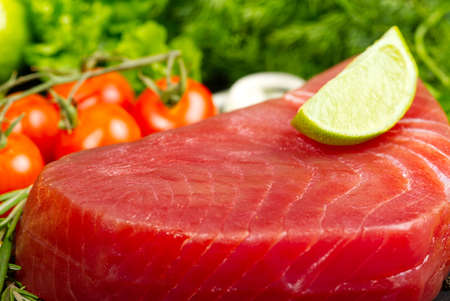 Raw tuna fillet steak with dill, lemon and spices in olive cutting board, ready for cookingの写真素材