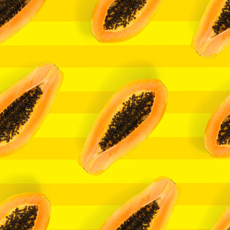 Fresh ripe papaya seamless pattern on yellow background. Tropical abstract background. Top view. Creative design, minimal flat lay concept. Trend tropical fruit food background patternの写真素材