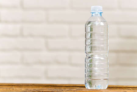 Drinking water in plastic bottle on wooden table and white wall. Health concept. clean water in...