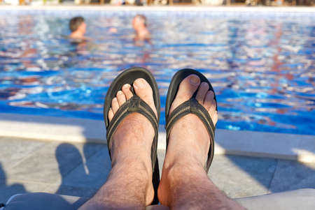 feet in front of blue water in open swimming pool in summer sunny dayの写真素材