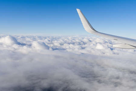 View of airplane white wing flying in blue sky over clouds. Travel conceptの写真素材