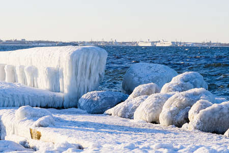Winter on shore of the Baltic Sea. Lighthouse in ice. Baltic Sea and frozen pier in winter, Estonia,...