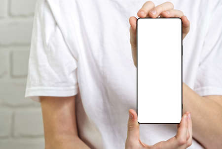 Happy smiling boy showing smartphone mockup in a white backdrop. mobile phone , cellphone screen...