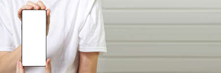 Happy smiling boy showing smartphone mockup in a white backdrop. mobile phone , cellphone screen mockupの写真素材