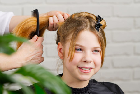 Hairdresser making a hair to cute girl in hair salon. Young girl at hairdresser. beauty salon conceptの写真素材