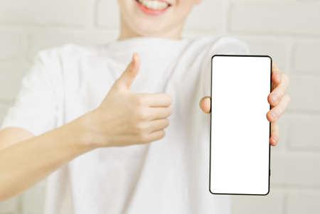 Happy smiling boy showing smartphone mockup in a white backdrop. mobile phone , cellphone screen...