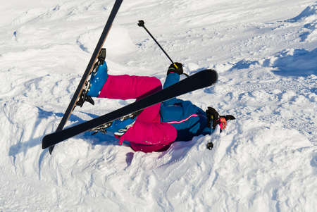 A woman fell on skis from a mountain in the snow. high-risk activity or extreme sport insurance concept. skier fell in alpsの写真素材