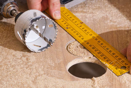 Worker with milling cutter in action at the workshop. Carpenter making holes in the wood board. Man...