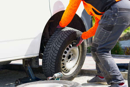 Mechanic changing car tire with tool. road help, changing and repairing tire, wheel. replacing tire...