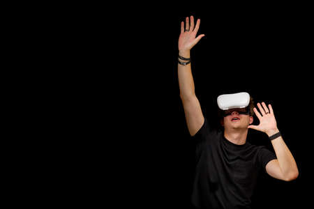 Young man wearing virtual reality VR glasses, goggles isolated on black background. Inside A...