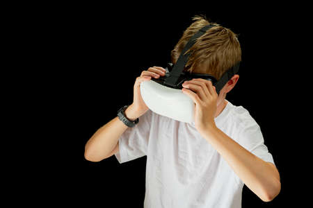 Portrait of young Boy playing VR game in black background. Young hipster wearing VR headset, half body shot. Young generation choose virtual reality, metaverse relaxation concept. remote education conceptの写真素材