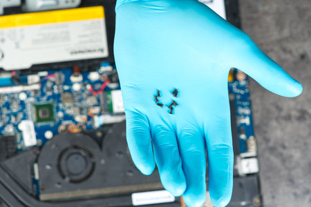 Hands of a technician repairing a broken laptop computer. Laptop repair service. Engineer fixing...