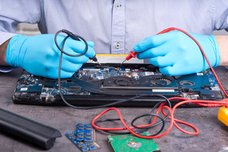 Hands fixing motherboard of pc or laptop notebook close up in service. Laptop repair service. PC hardware upgrade and maintenance. Engineer fixing broken notebook.の写真素材