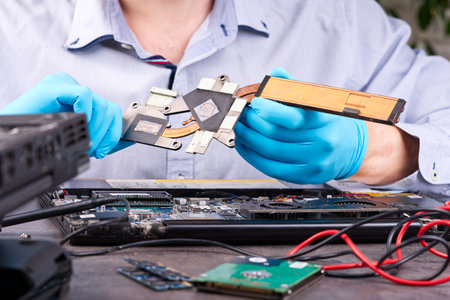 Hands fixing motherboard of pc or laptop notebook close up in service. Laptop repair service. PC hardware upgrade and maintenance. Engineer fixing broken notebook.の写真素材
