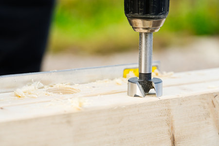 Carpenter drilling holes in the wood beam. wooden frame domestic house building. drilling a hole...