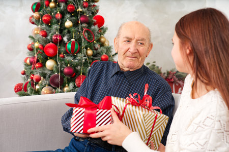 great grandfather and great granddaughter. grandfather getting christmas gift from granddaughter. happy elderly man getting a beautiful present. christmas, xmas, holidays, people and family conceptの写真素材