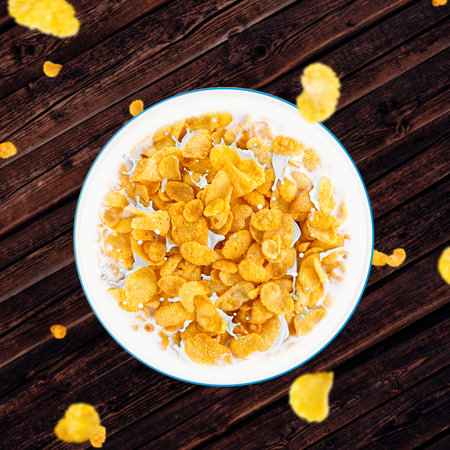 Bowl of sweet cornflakes with milk on dark wooden table background, top viewの写真素材