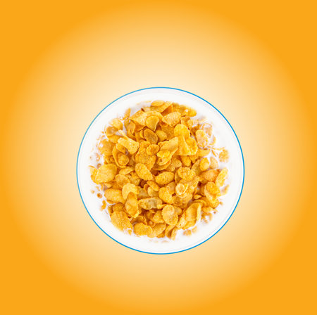 Bowl of sweet cornflakes with milk on orange background, top view