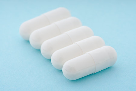 Gel capsule. White medicine capsule on light blue background. food supplement, pharmacy concept.の写真素材