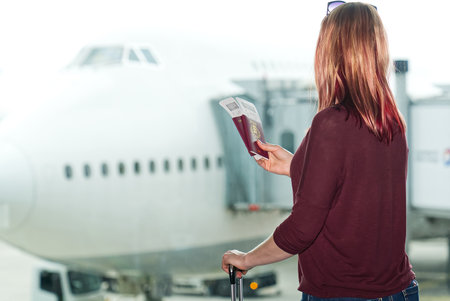 Woman at the airport window and flight departure, Airport Terminal: Happy Traveling Looks Aroundの写真素材