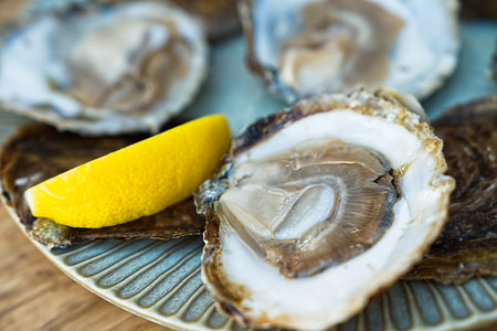 Fresh oysters served on a plate with lemon on old wooden table. Oysters served in fish restaurantの写真素材