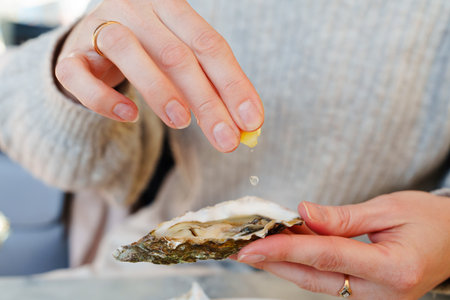Eating oysters and lemons at an outdoor luxury picnic - a girl enjoying a gastronomic treatの写真素材
